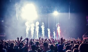 Vibrant concert scene with cheering crowd and bright stage lights creating an electric atmosphere.